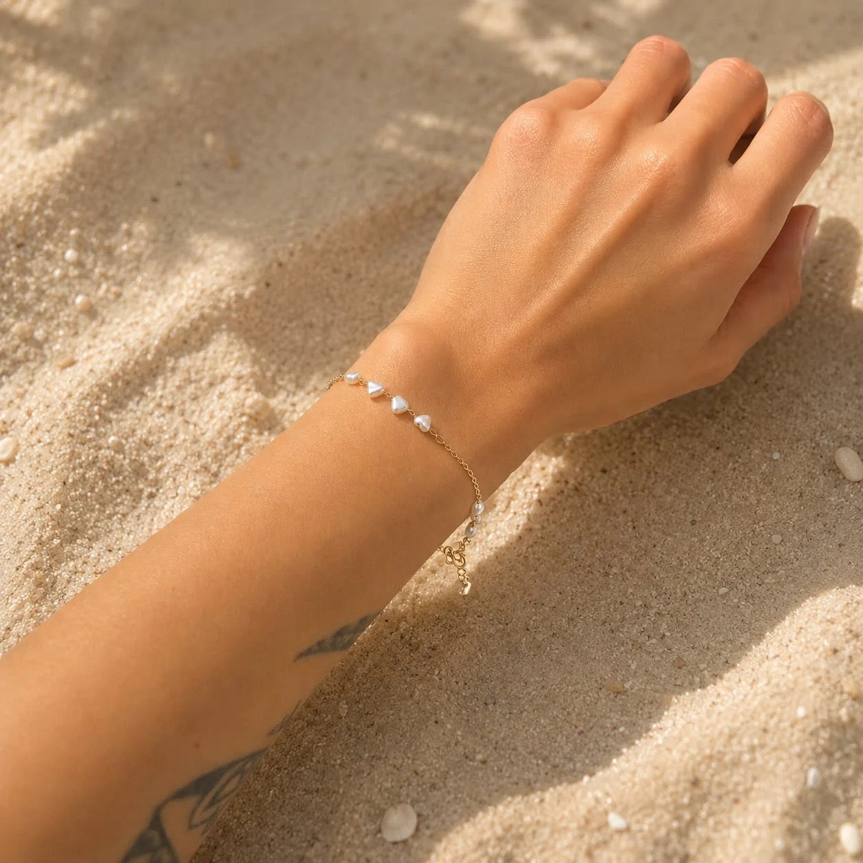 Heart-shaped pearl station bracelet worn on wrist