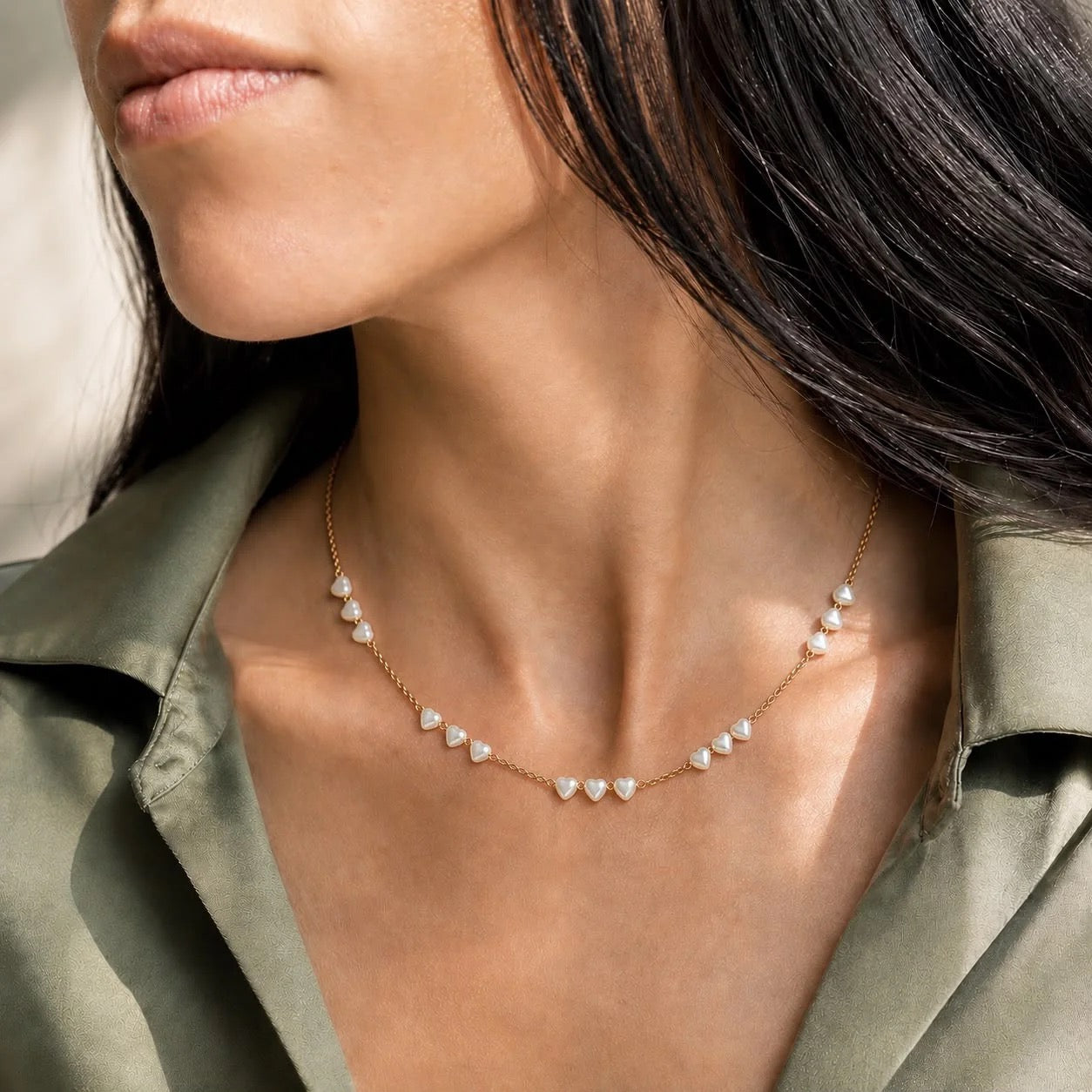 Heart-shaped pearl station necklace worn on neck