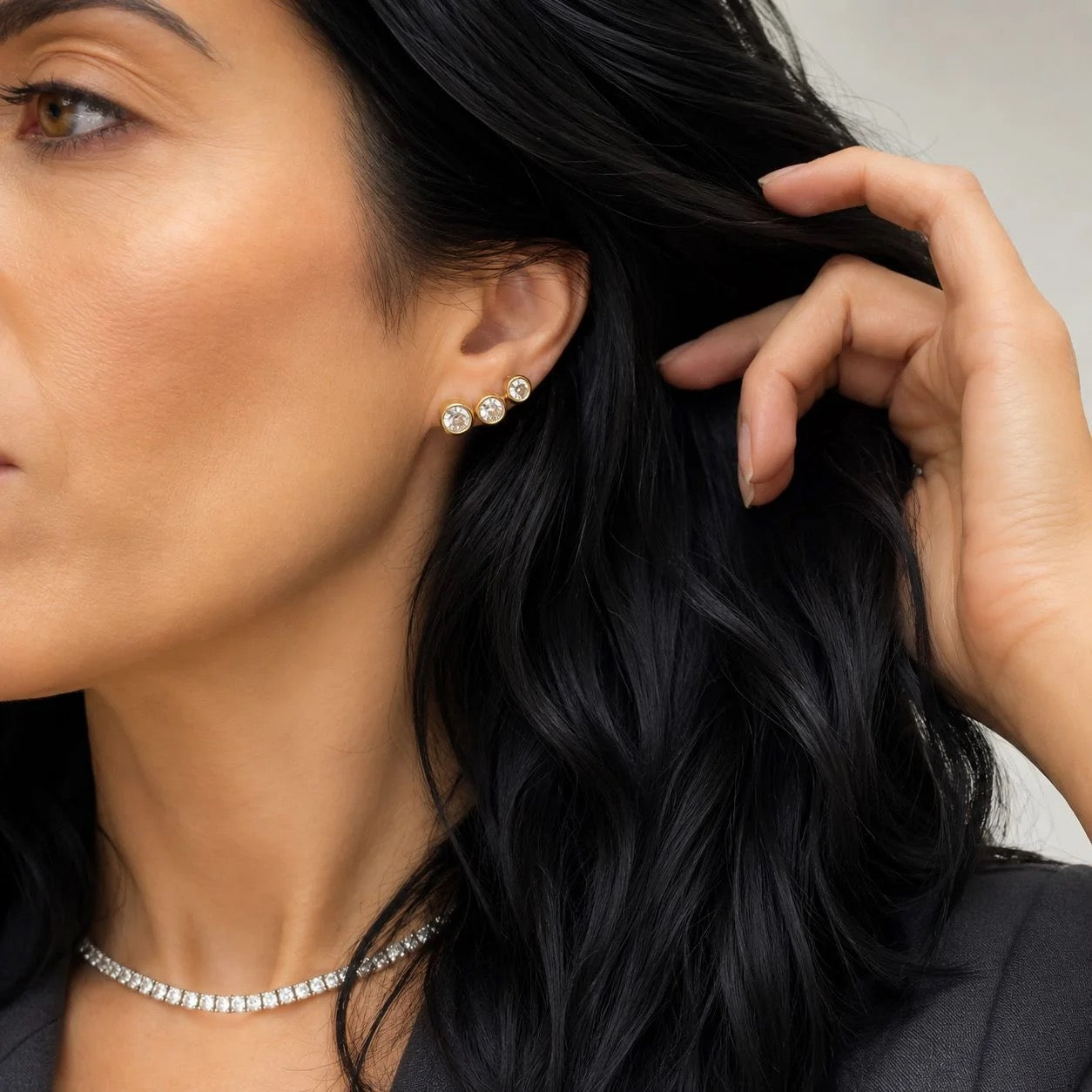 Gold-finish classic bezel cubic zirconia stud earrings worn in an ear stack