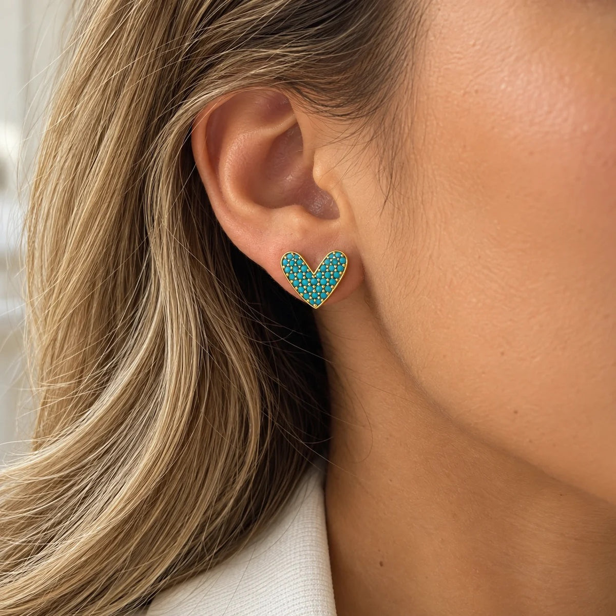 Close-up of a model wearing an SR OF GOLD CORA turquoise-colored heart stud.