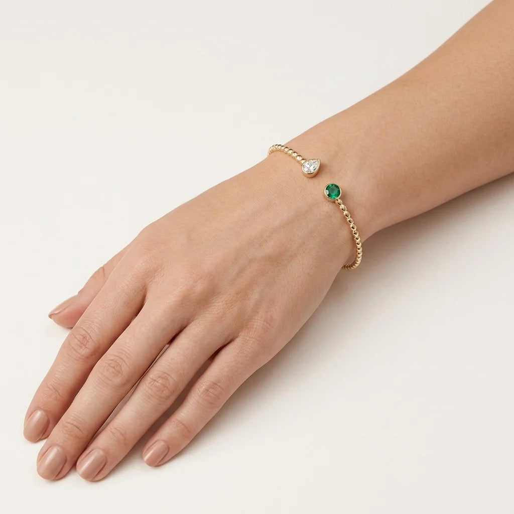 Lustrous 14K solid gold bracelet with diamond and emerald worn on wrist