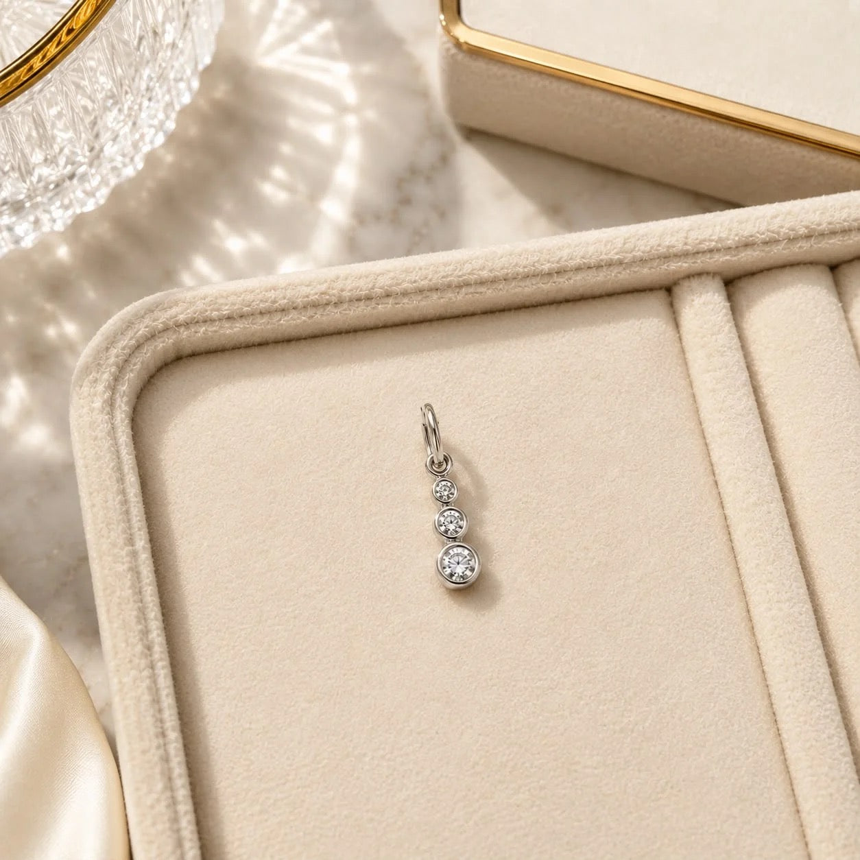 Rhodium-filled graduated CZ drop charm displayed in jewelry tray