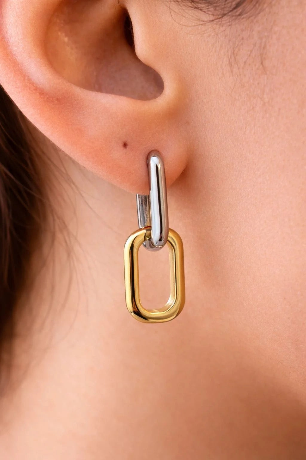 Two-tone paperclip link drop earring worn on ear